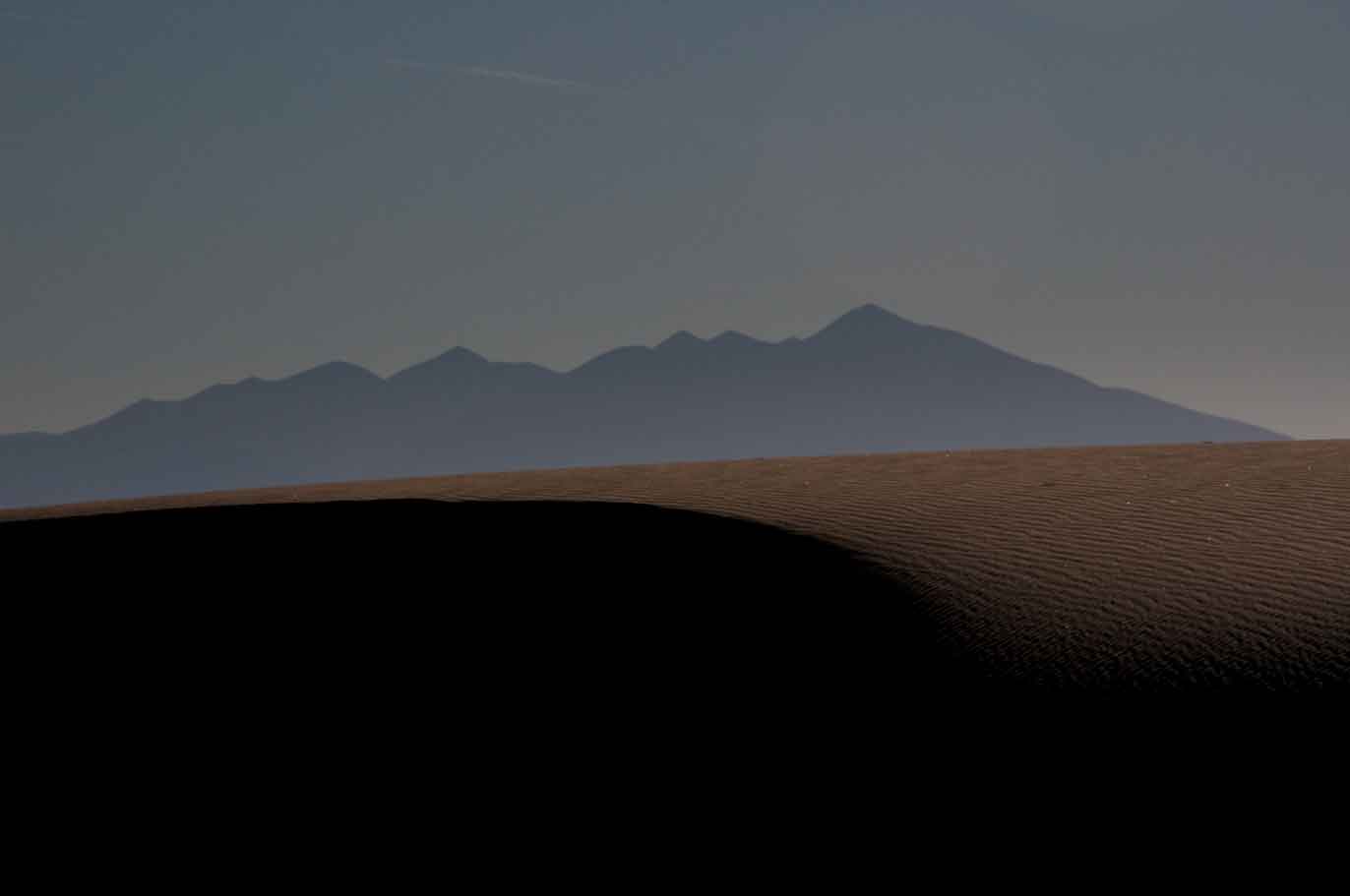 Sand dune in the Arizona high desert, on the Navajo Nation with the San Francisco Peaks in the distance